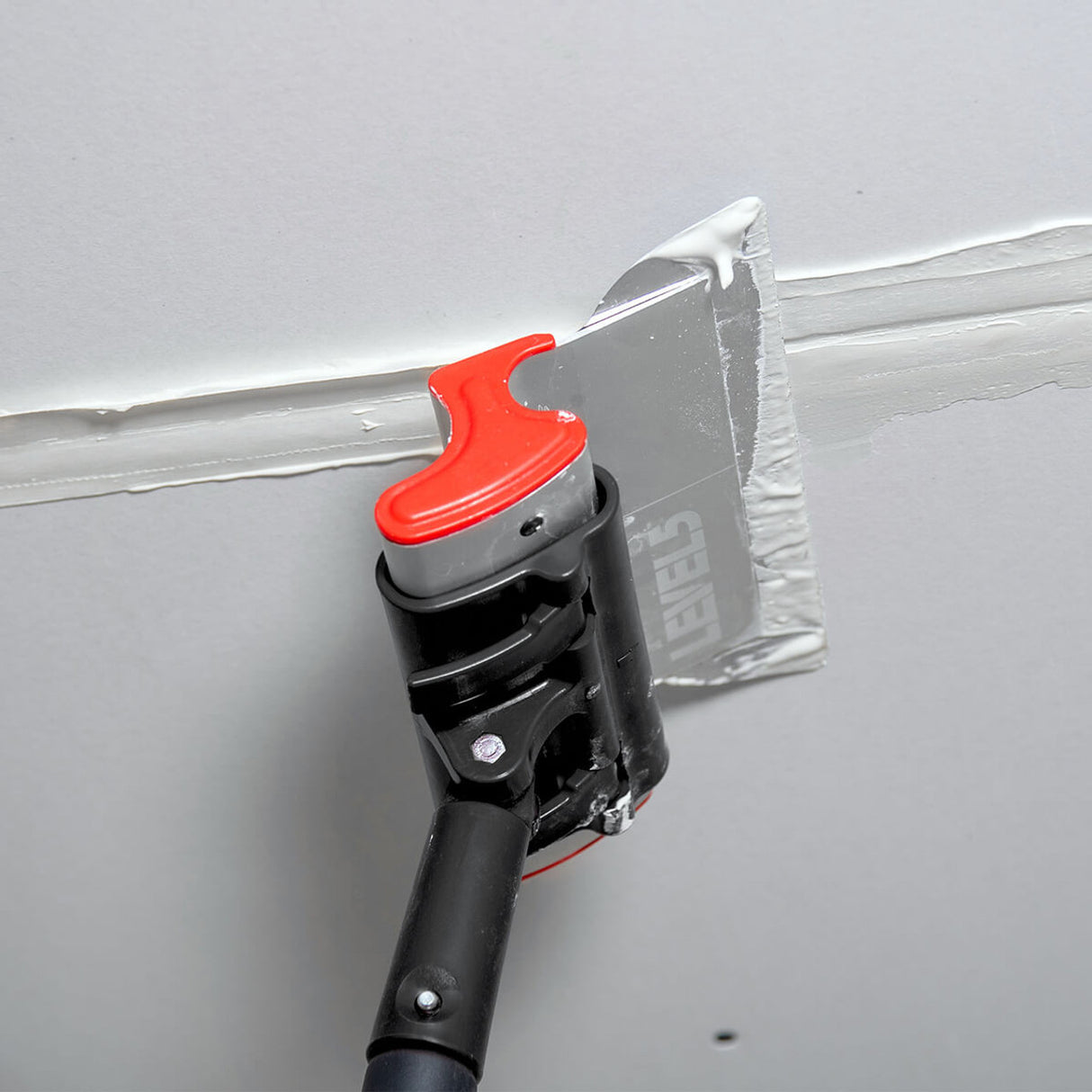 Level 5 skimming blade pole adaptor attached to a painter’s pole, holding a Level 5 smoothing blade feathering a mud coat on a joint
