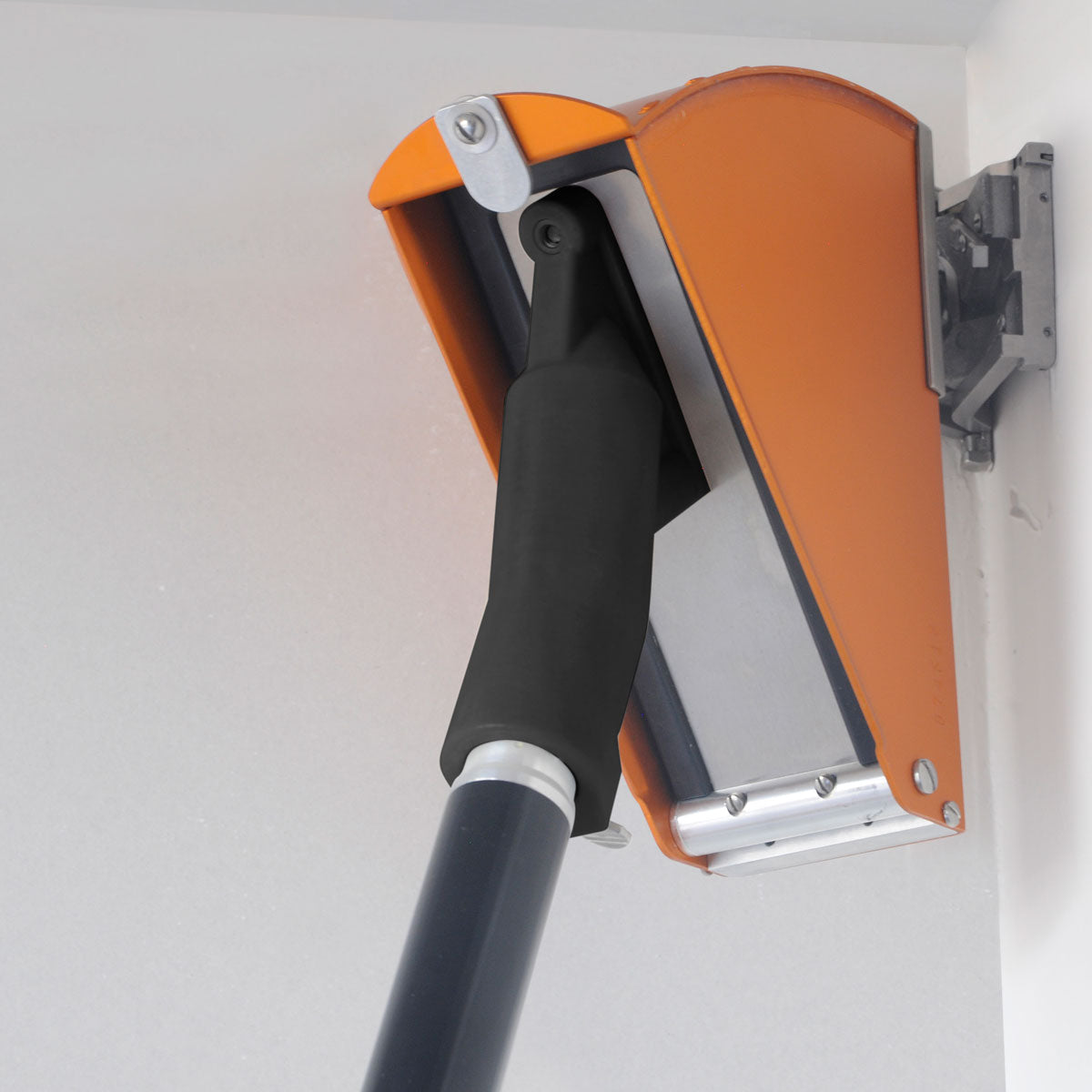 Back view of a TapeTech Corner Applicator Box attached to a handle and corner finisher, smoothing mud on a wall corner