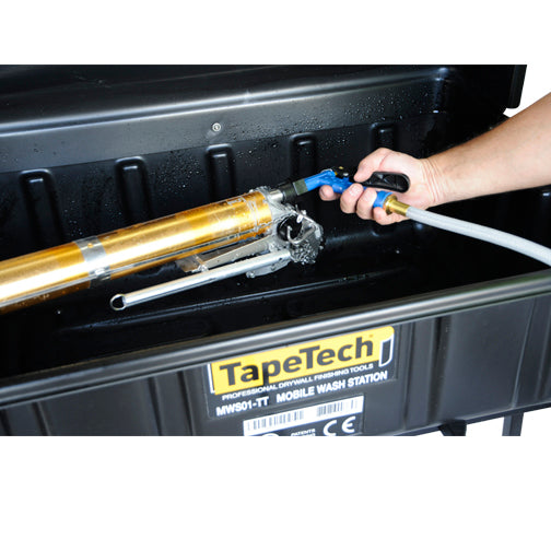 Close-up of a person using a TapeTech water sprayer to clean a TapeTech taper inside a wash basin
