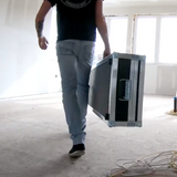 Person walking through job site holding a large black Columbia automatic taping tool case with rubber feet and rolling wheels