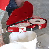 Open Level 5 banjo with tape roll inside being filled with mud from a bucket on the job site